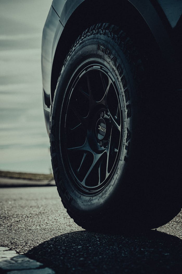 Detailed shot of a car wheel with a textured tire on a street.