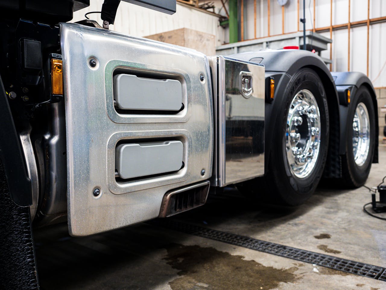Detailed view of truck wheels and metallic detailing in an indoor workshop setting.