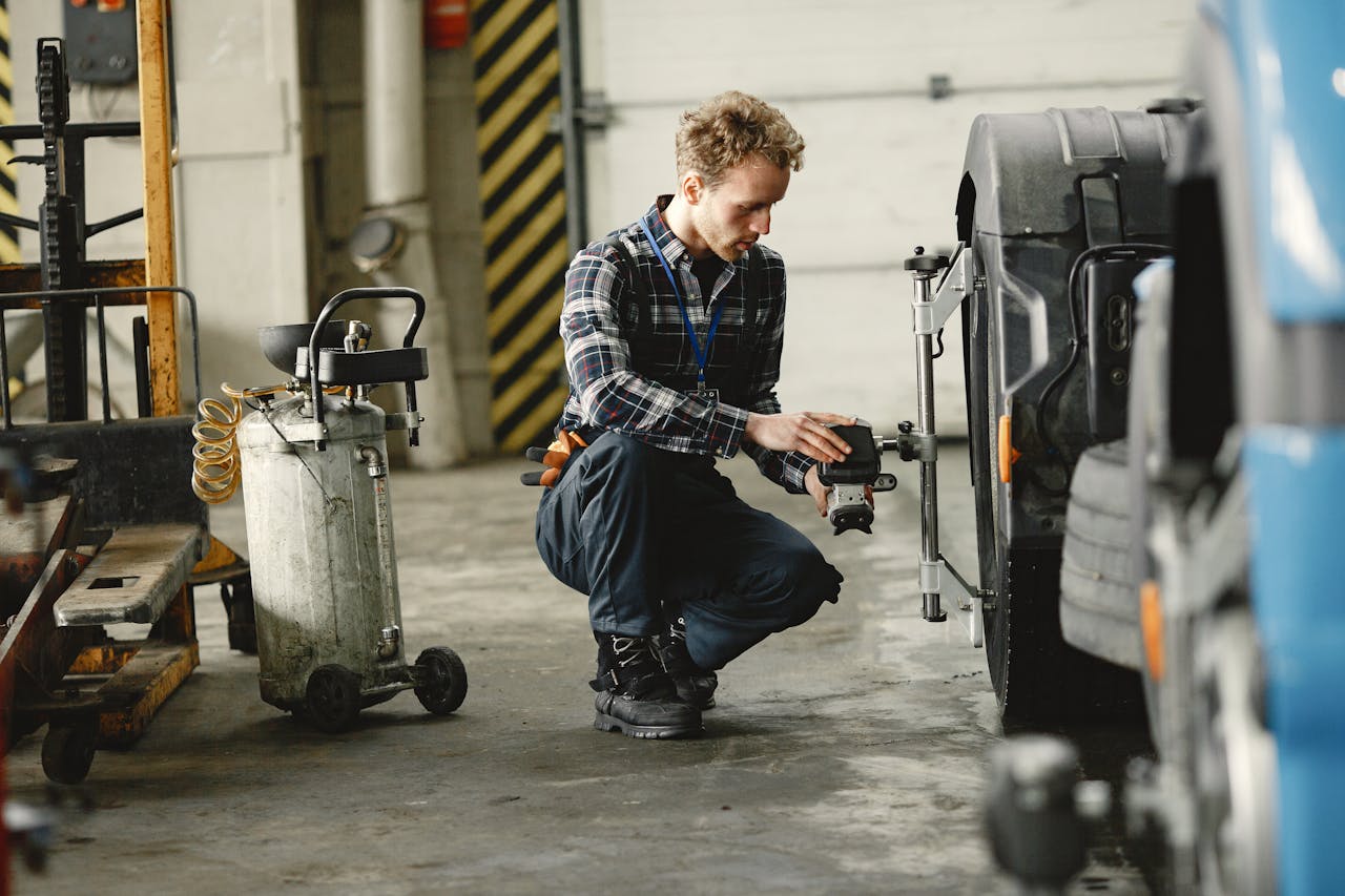 A mechanic in a workshop aligning truck wheels, focusing on precision and repair.